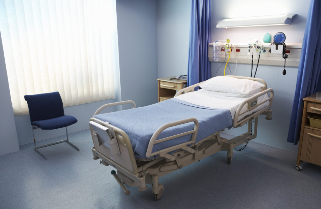 A hospital room--the bed is empty, and the sheets are neat.
